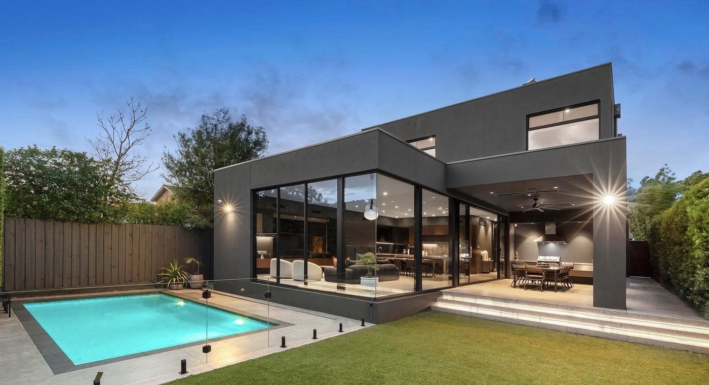 Twilight view of a contemporary Melbourne home with floor-to-ceiling glazing and pool after a Pristine clean