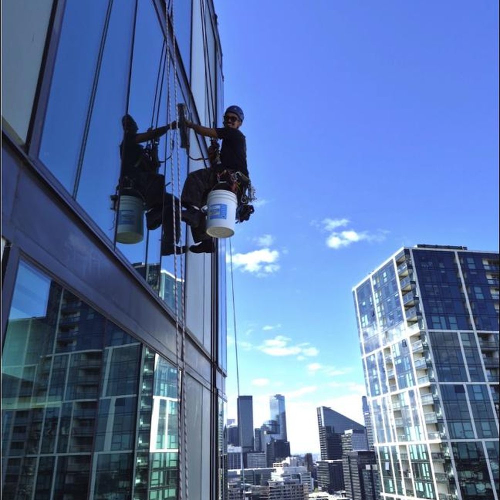 Rope access window cleaning technician high above Melbourne skyline