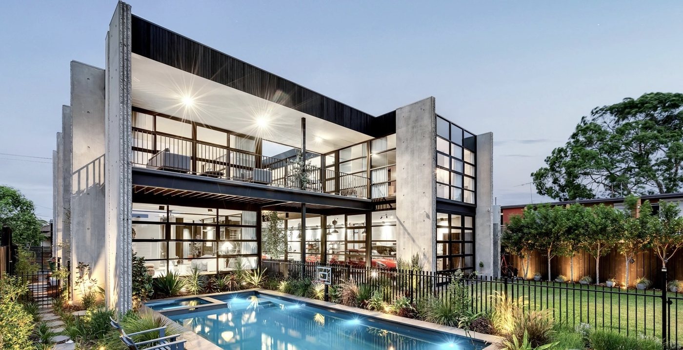 Twilight exterior of a modern Melbourne home with full-height glazing and pool, cleaned by Pristine