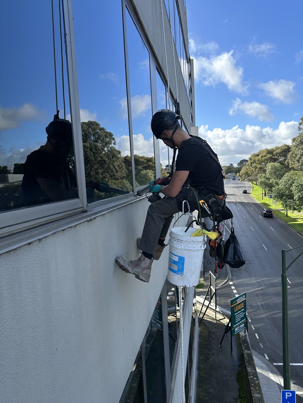 IRATA rope access technician applying perimeter sealant to a window frame on a Melbourne building facade