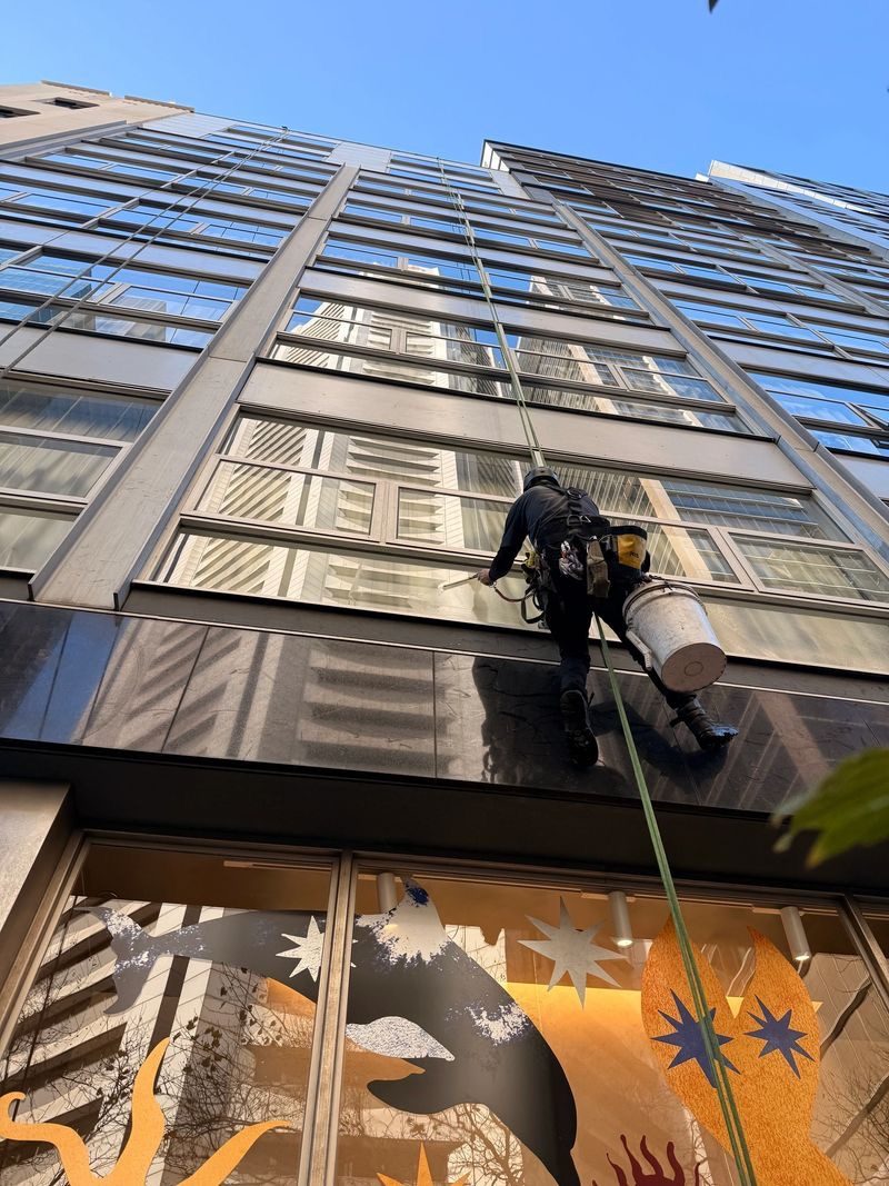Pristine technician abseiling a Melbourne high-rise, cleaning glass at height